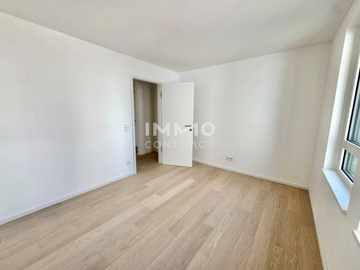 Leeres Zimmer mit hellem Holzparkettboden und viel Tageslicht durch das Fenster.