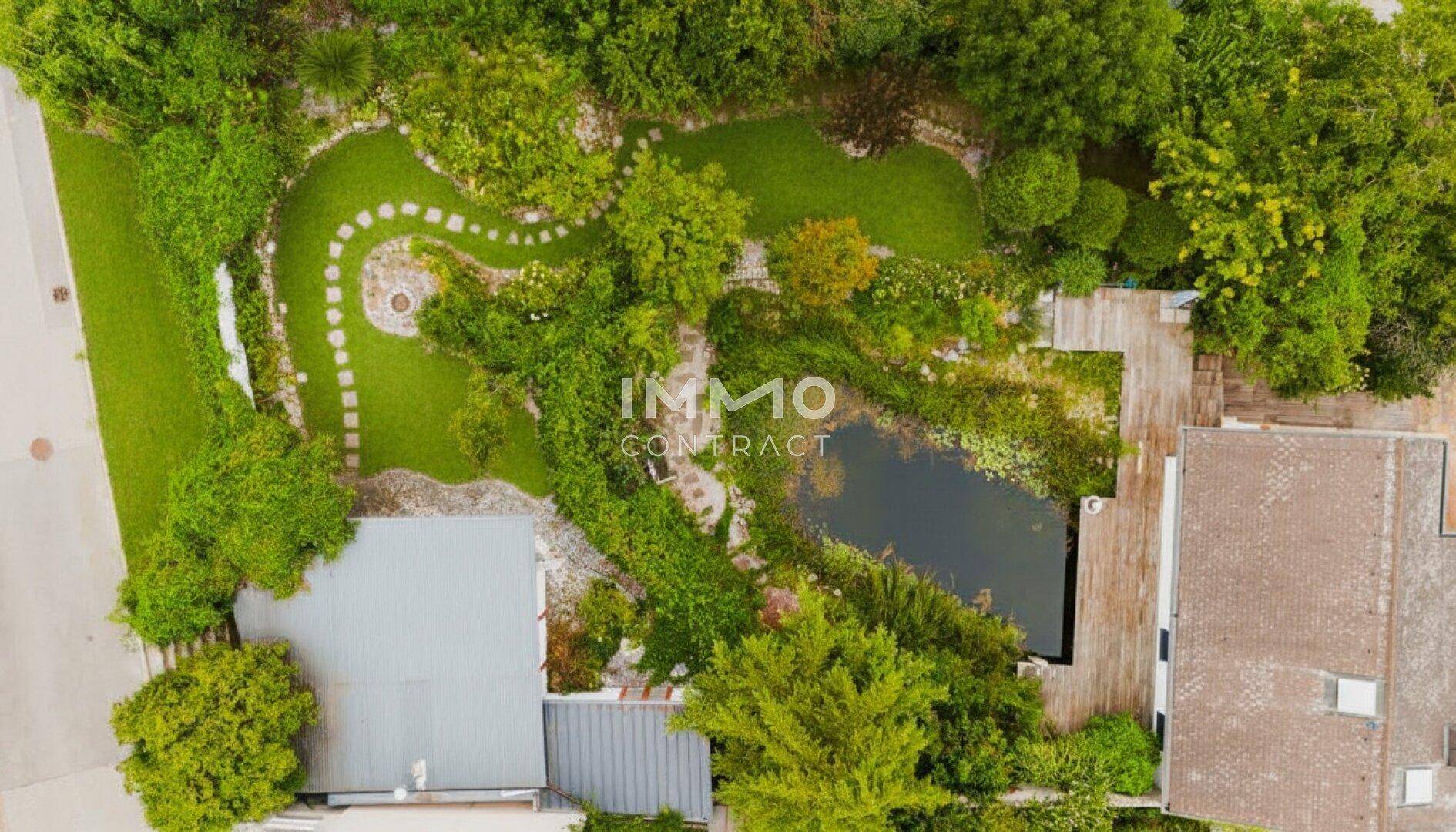 Detailansicht des Gartens von oben mit geschwungenen Wegen, Rasenflächen und Naturpool.