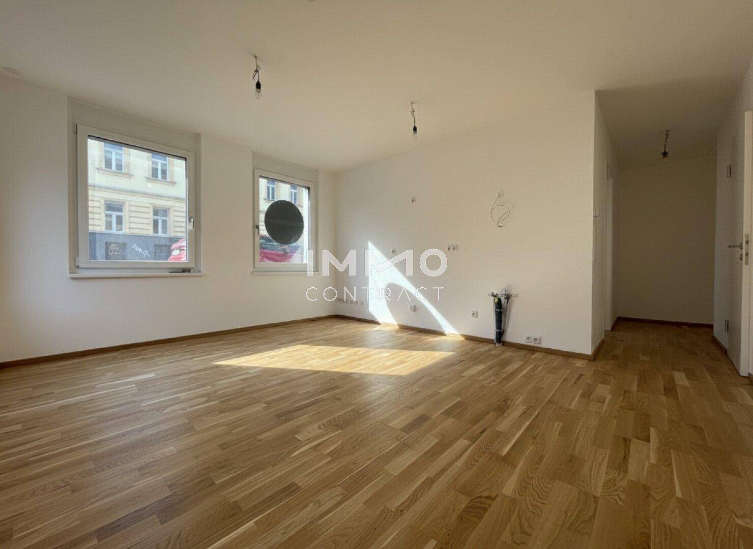 Geräumiger, leerer Raum mit Holzboden und Fenstern, die eine helle Atmosphäre schaffen und viel Potenzial bieten.