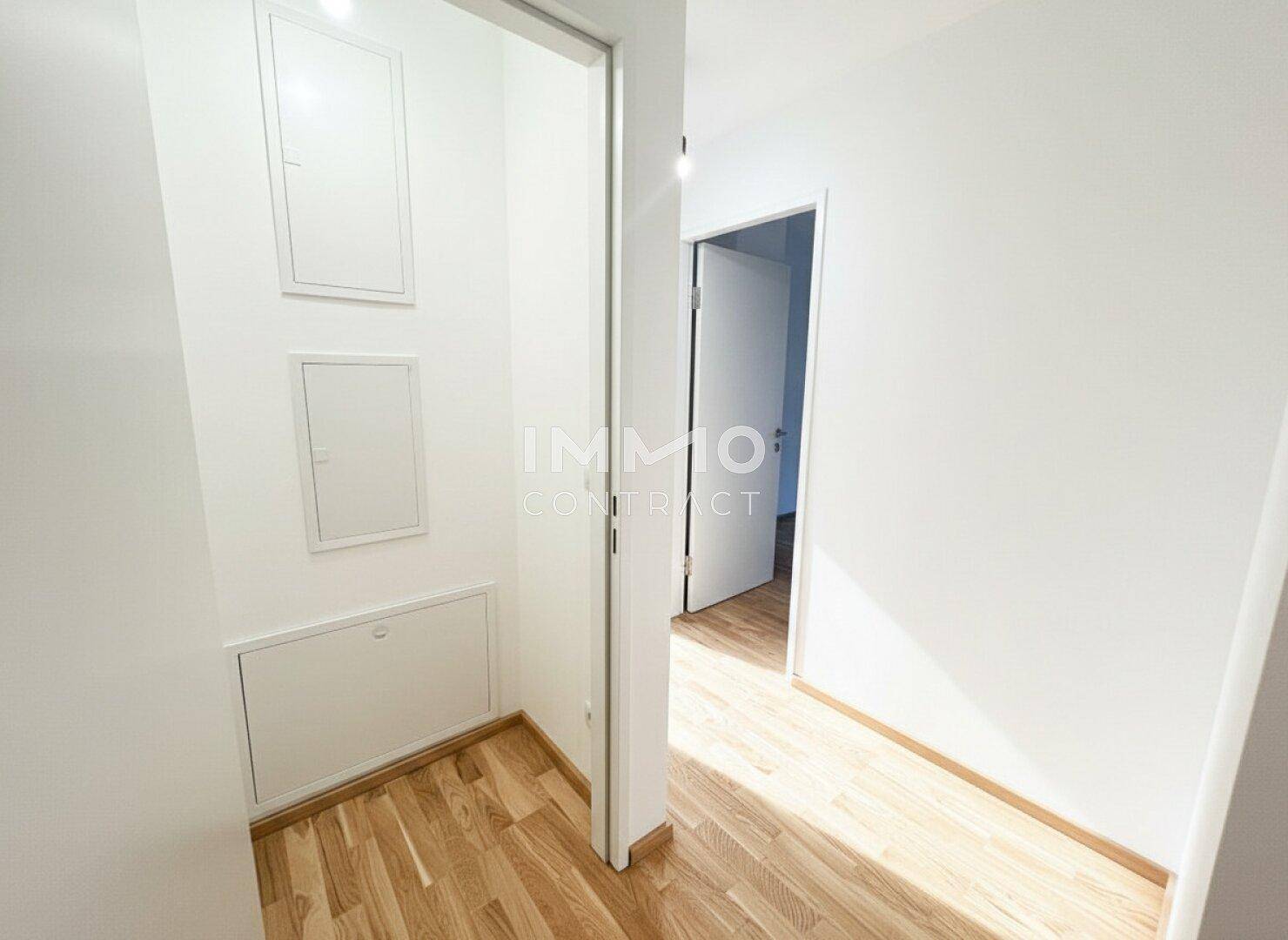 Heller Flur mit Holzboden und weißen Wänden, der zu weiteren Räumen führt und einladend wirkt.