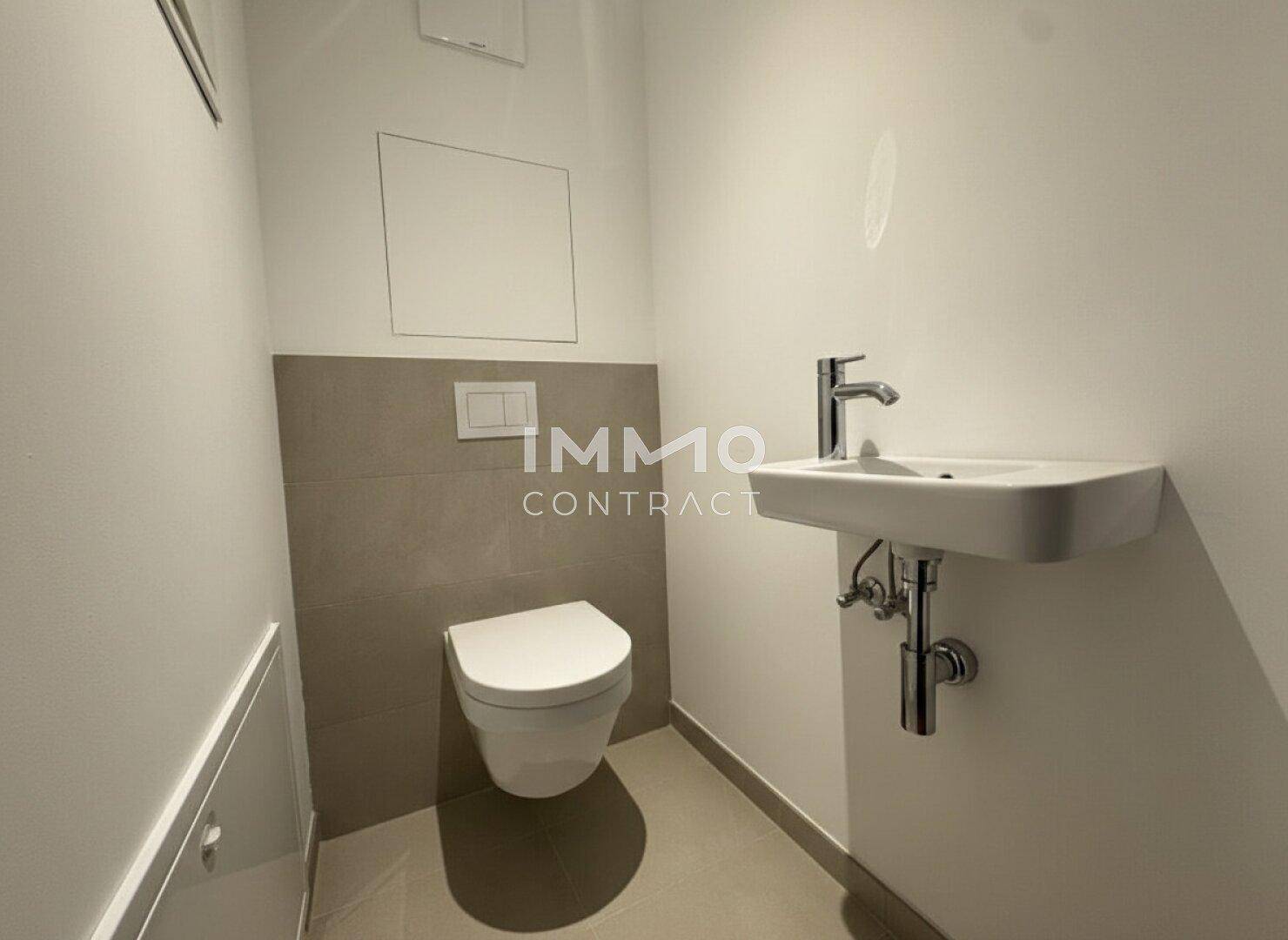 Separates Gäste-WC mit wandhängender Toilette und kleinem Handwaschbecken.