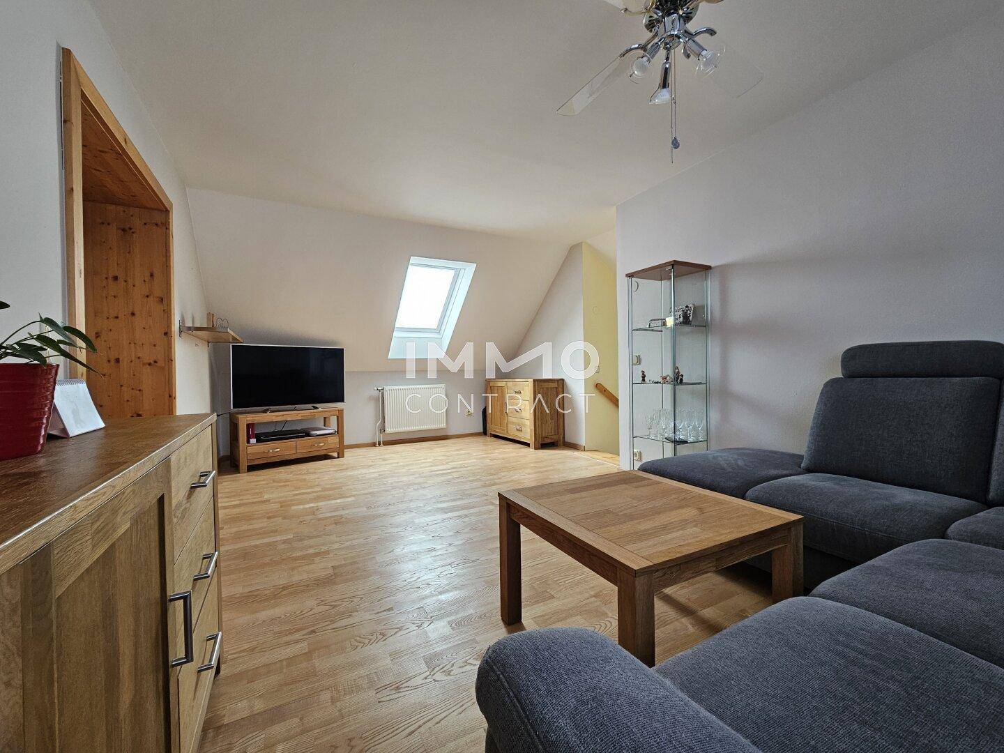 Gemütliches Wohnzimmer im Dachgeschoss mit Holzboden, Sofa und Dachfenster für Helligkeit.