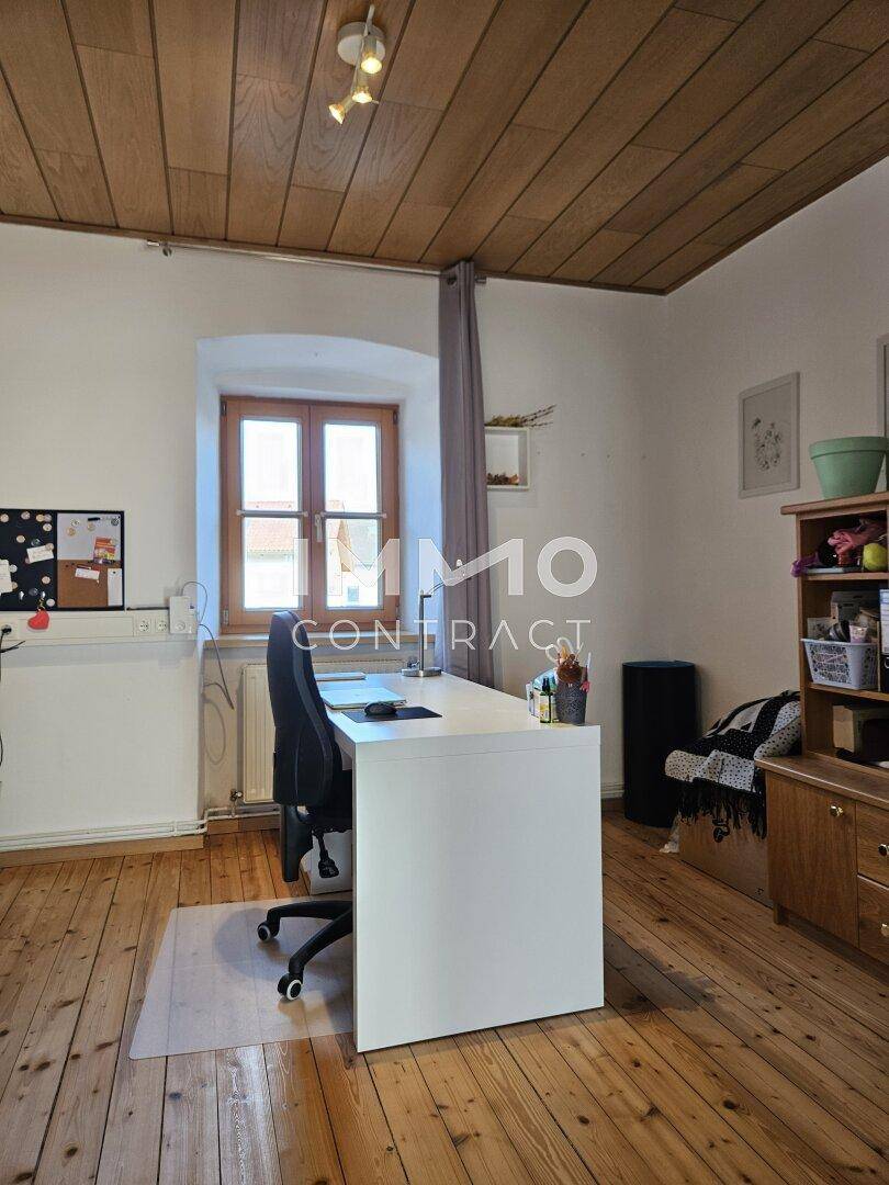 Arbeitszimmer mit Holzdielenboden, Holzdecke und einem Fenster mit Blick nach draußen.