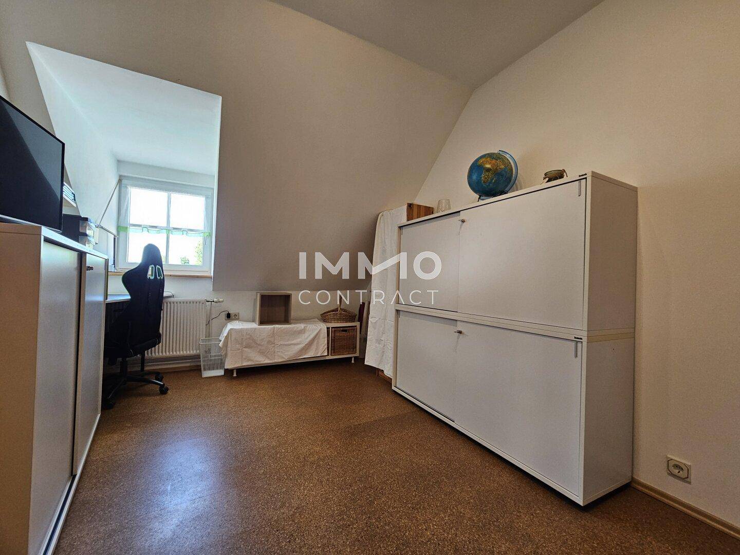 Helles Arbeitszimmer mit Korkboden, Schreibtisch und Stauraum unter der Dachschräge.