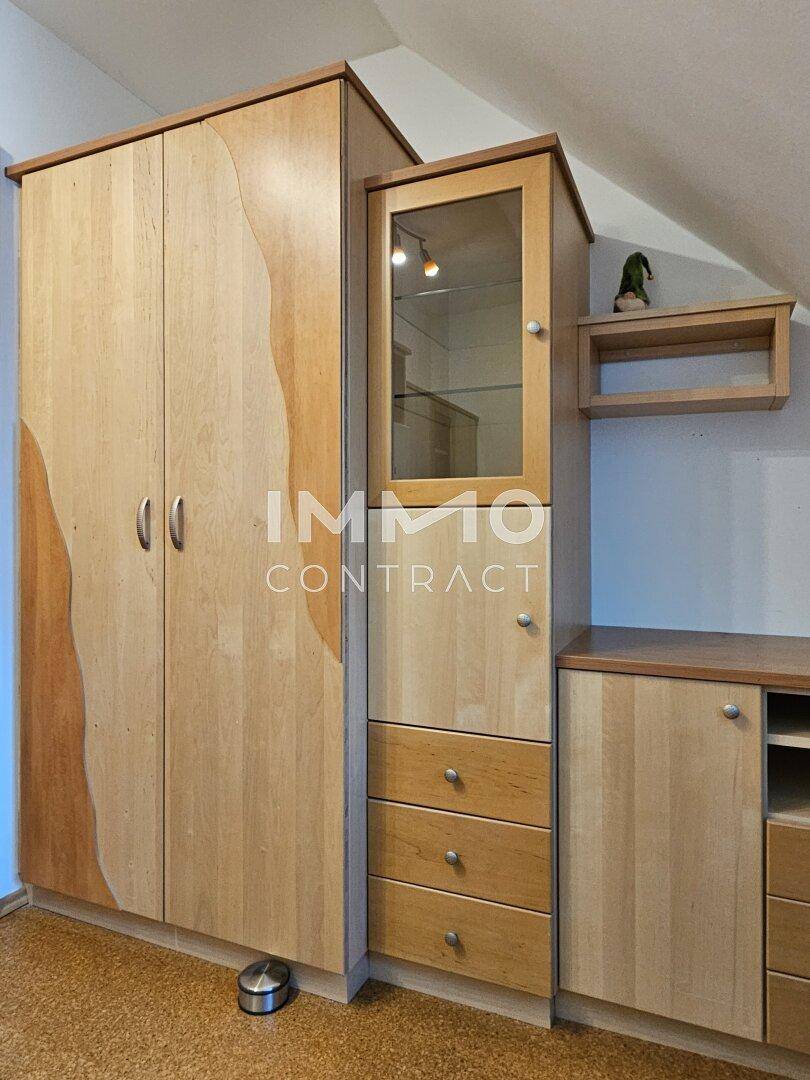 Praktische Einbauschränke aus Holz mit Glasvitrine und Schubladen im Schlafzimmer.