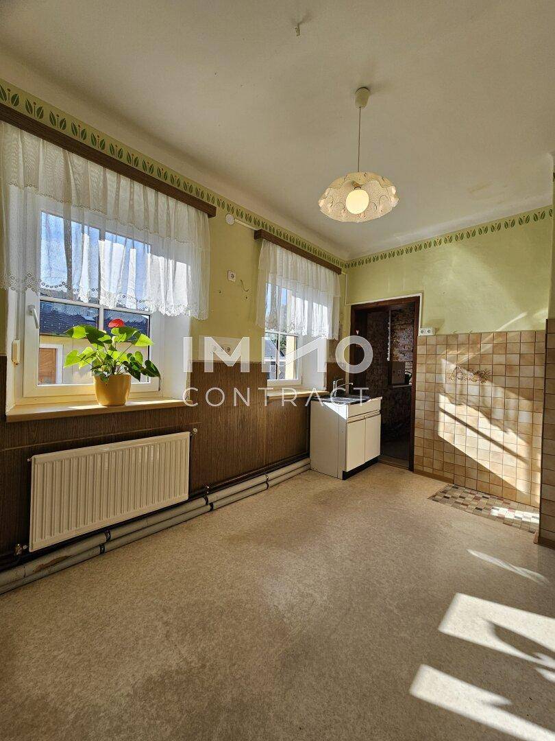 Einfacher Raum mit Spülbecken, Fenster und Heizkörper, möglicherweise eine Waschküche oder Speisekammer.