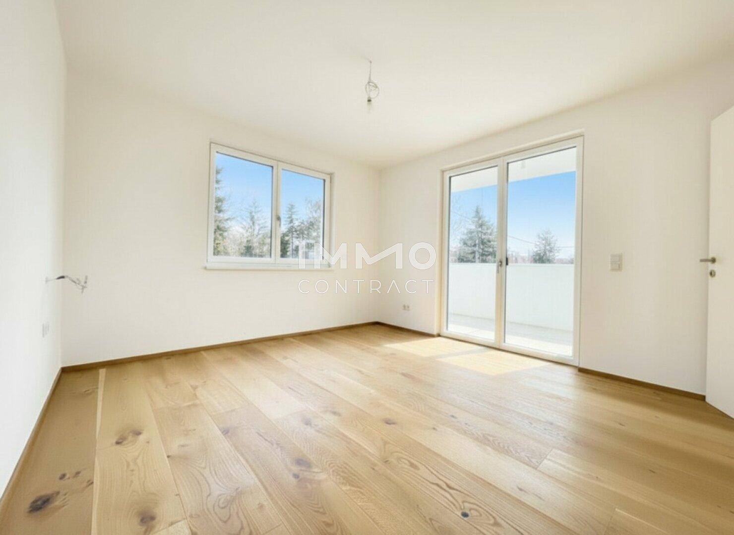 Lichtdurchflutetes Zimmer mit Holzparkettboden und direktem Zugang zum Balkon.