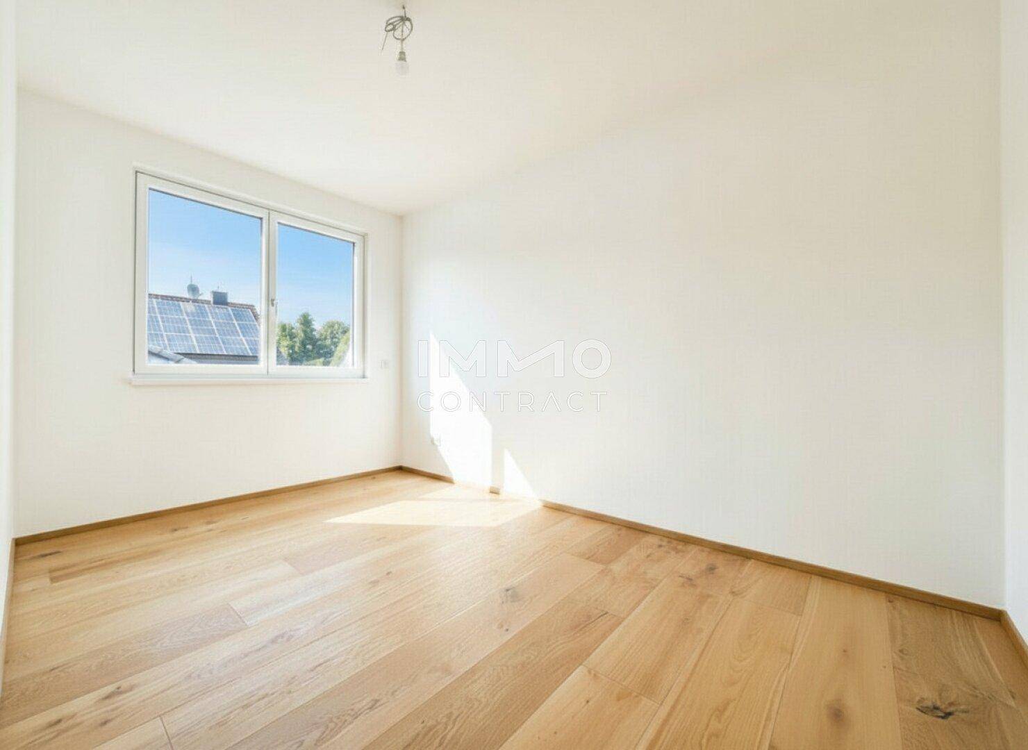 Helles Zimmer mit Holzparkettboden und großem Fenster, ideal als Schlaf- oder Arbeitszimmer.