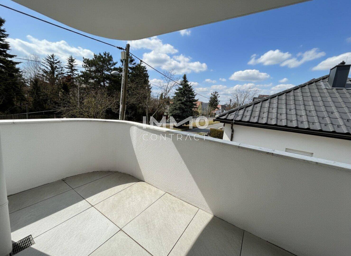 Sonniger Balkon mit Fliesenboden und freiem Blick auf die Umgebung.