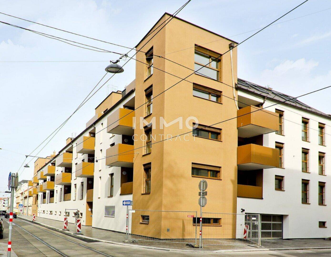 Moderne Wohnanlage mit markanter orangefarbener Fassade und zahlreichen Balkonen.