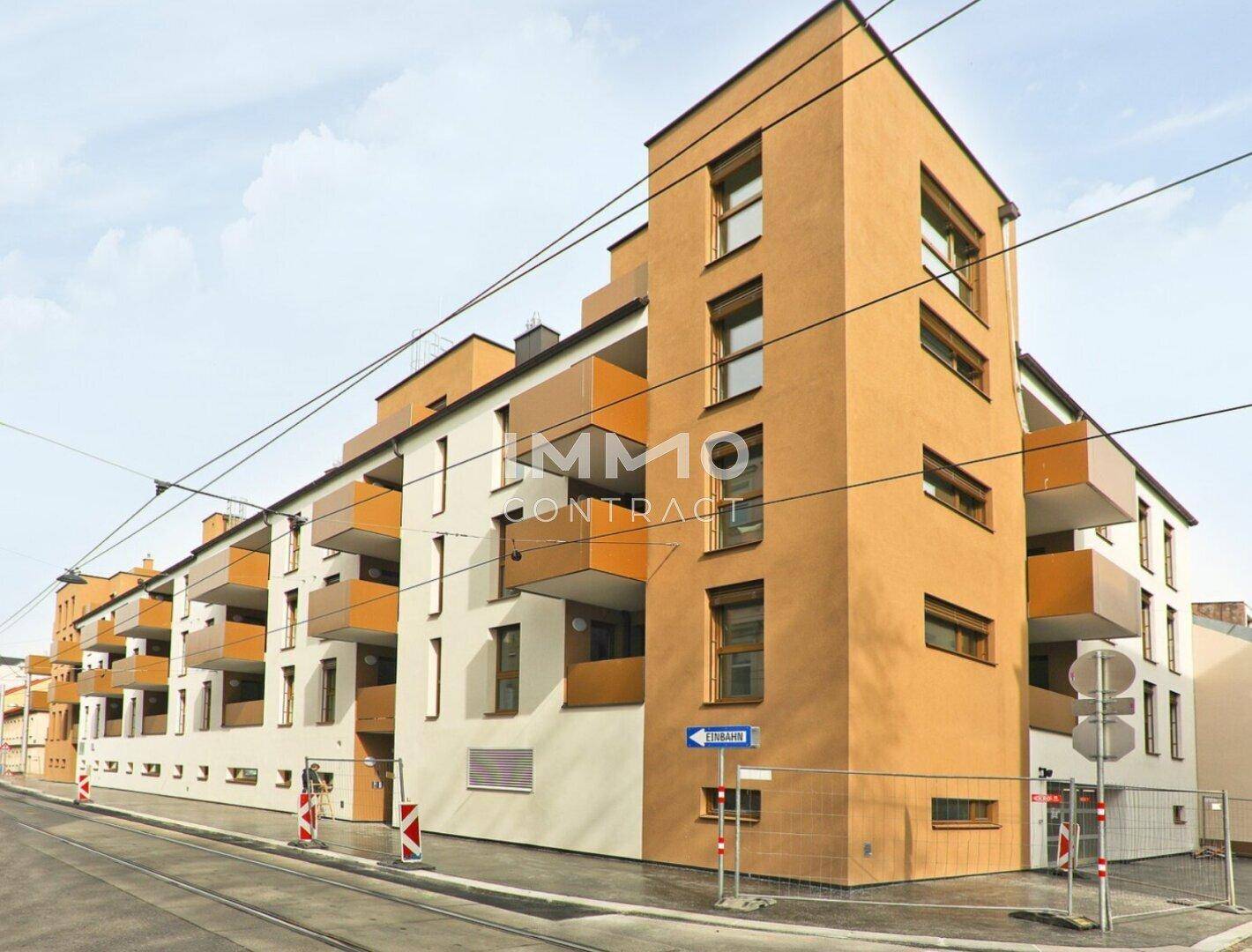 Neubau-Wohngebäude mit zeitgenössischer Architektur, orangefarbenen Akzenten und Balkonen.