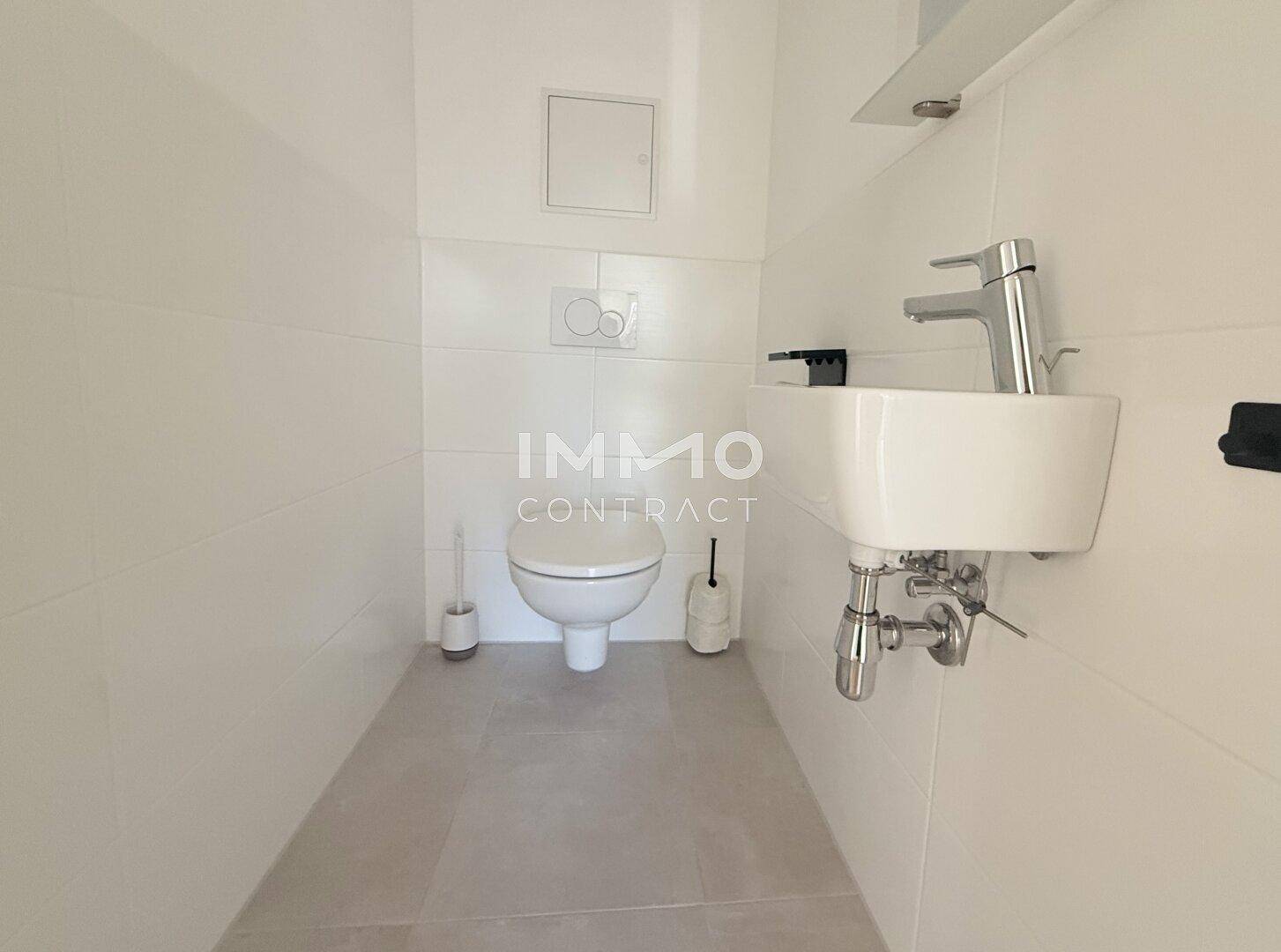 Separates Gäste-WC mit wandhängender Toilette und kleinem Handwaschbecken.