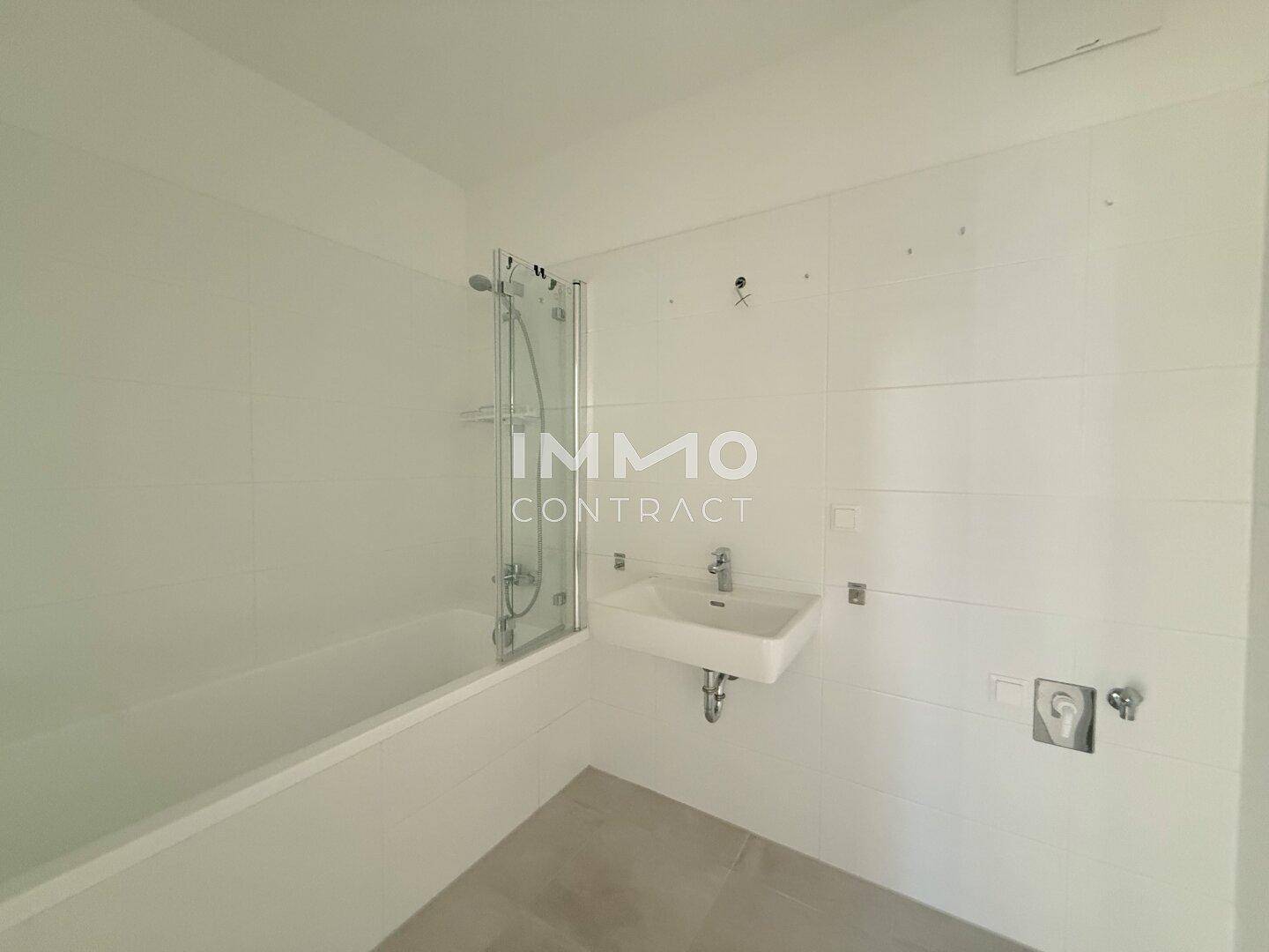 Modernes Badezimmer mit Badewanne, Dusche und Waschbecken, hell gefliest.