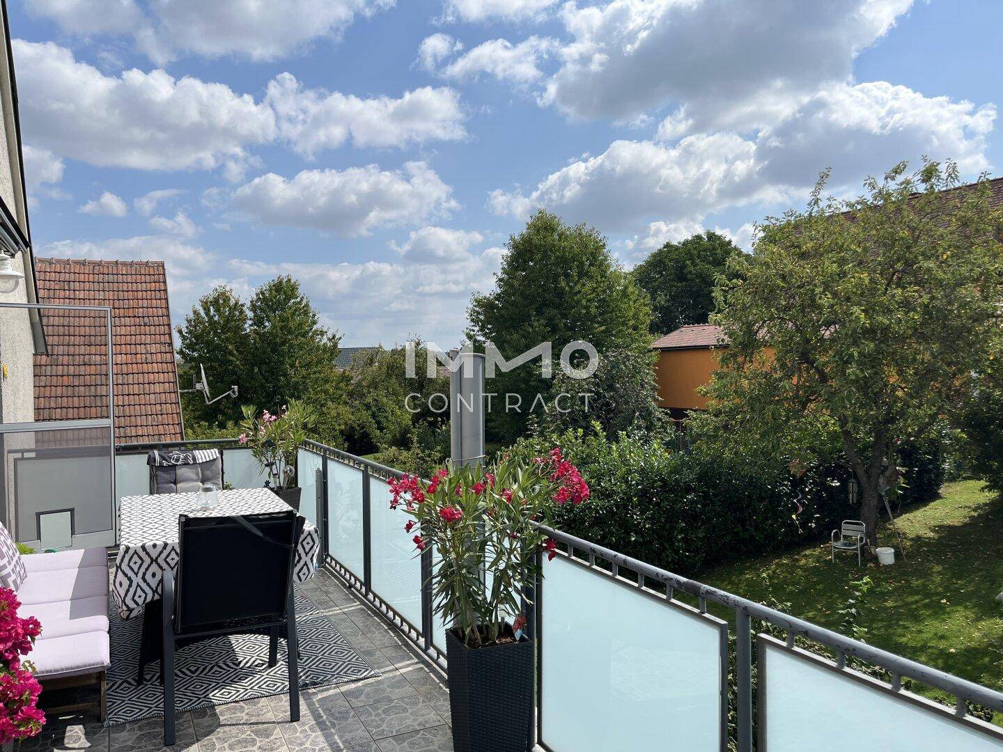 Möblierter Balkon mit Esstisch und Pflanzen, bietet einen weiten Blick ins Grüne und auf die Umgebung.