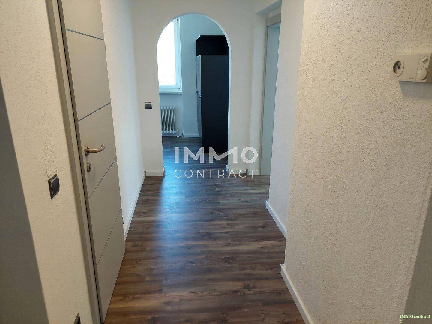 Heller Flur mit Laminatboden und einem eleganten Rundbogen, der zu weiteren Räumen führt.