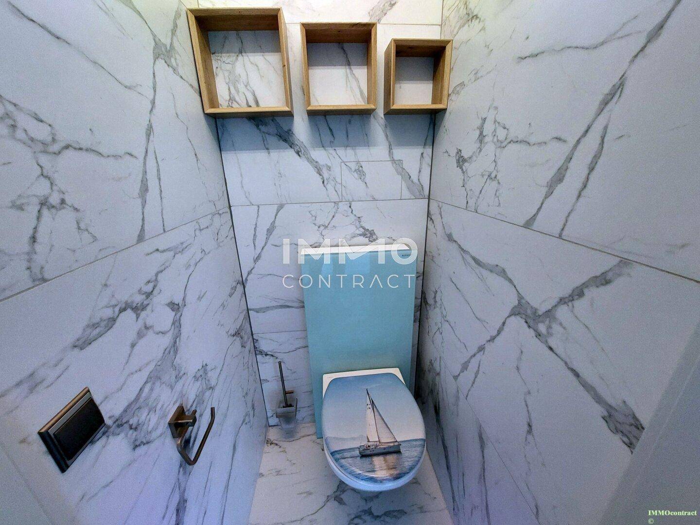Kleines WC mit Marmorfliesen, modernem WC und dekorativen Holzregalen.