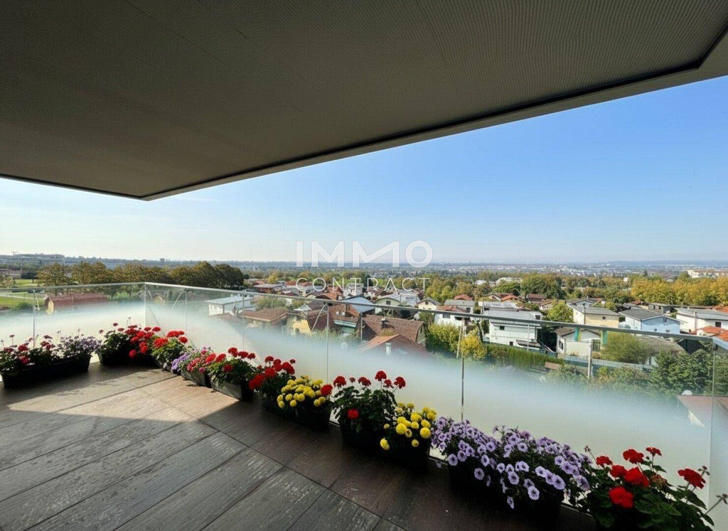 Geräumiger Balkon mit Blumenkästen und weitem Blick über die Stadtlandschaft.