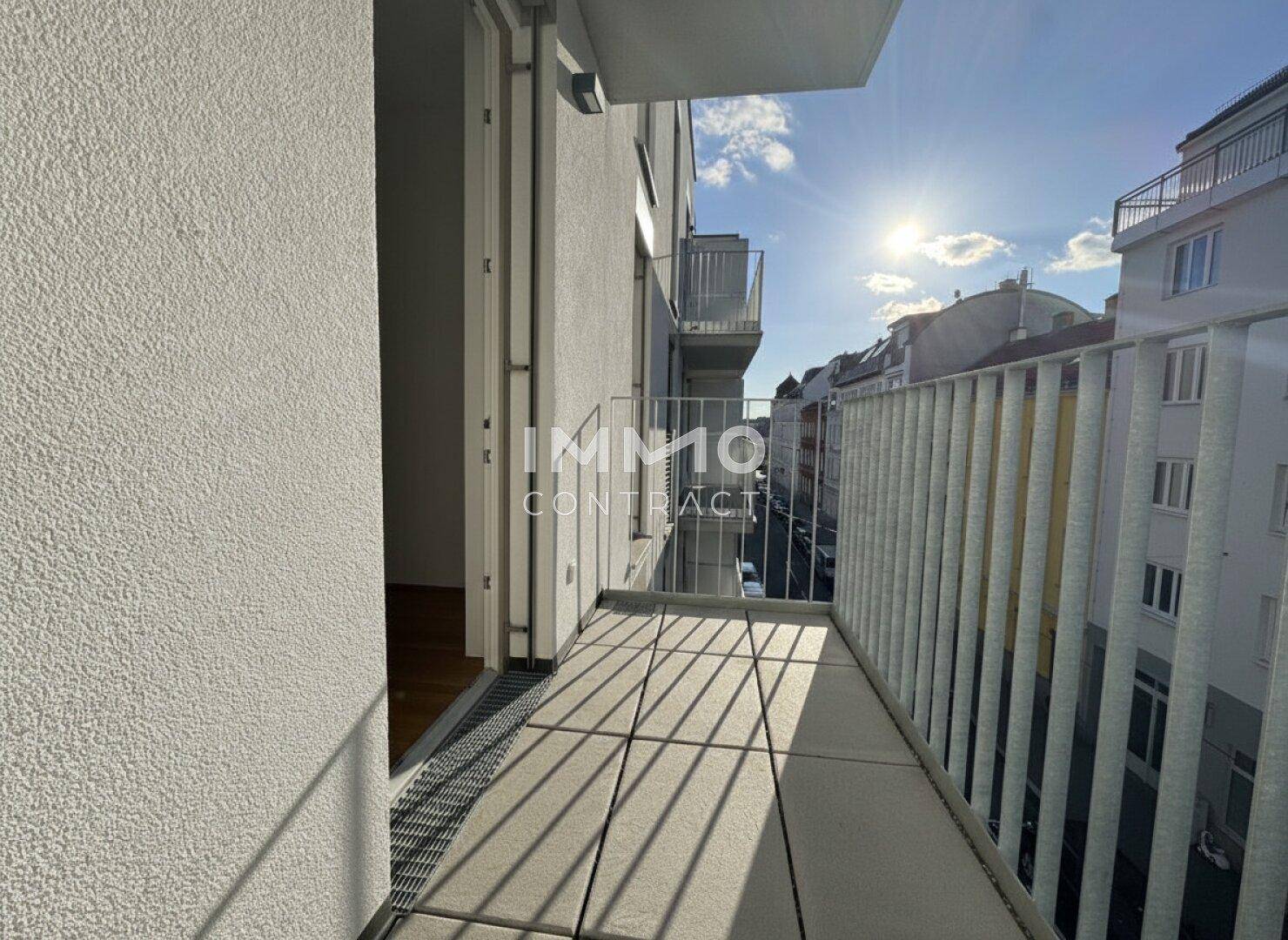 Schmaler Balkon mit Fliesenboden und sonnigem Blick auf die Straße.