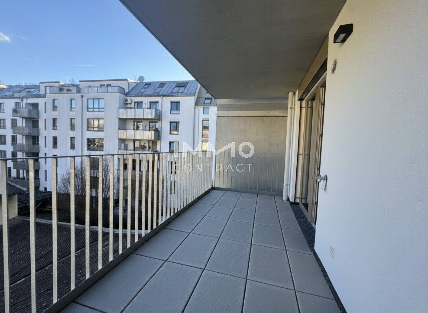 Geräumiger Balkon mit Fliesenboden und Blick auf die umliegenden Gebäude.