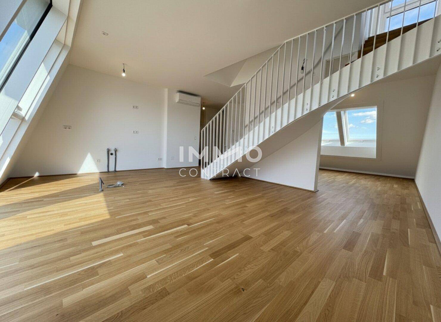 Geräumiger Wohnbereich mit Eichenparkett, moderner Treppe und viel Tageslicht durch Dachfenster.