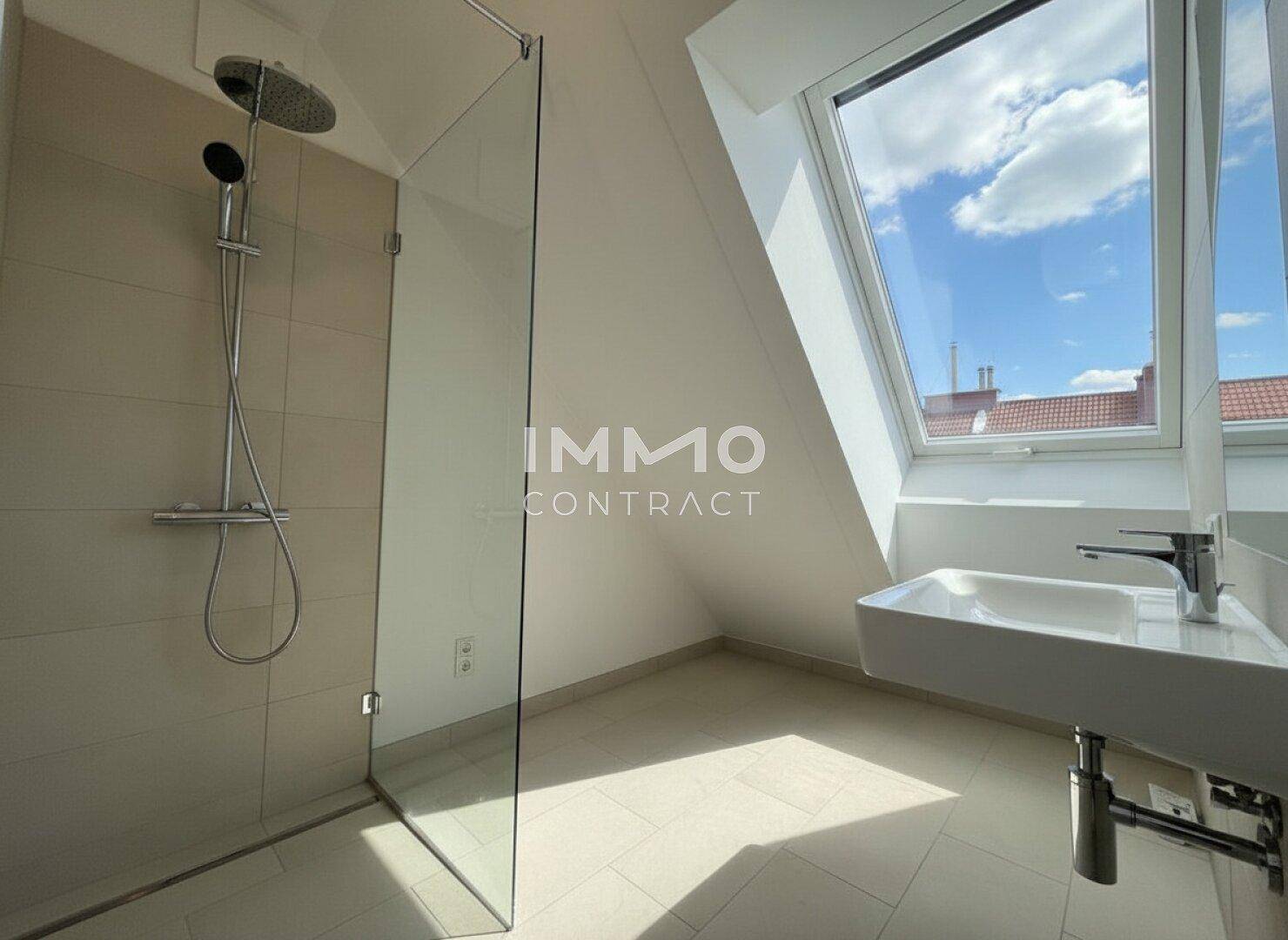 Modernes Badezimmer mit begehbarer Dusche, Wandwaschbecken und hellem Dachfenster.