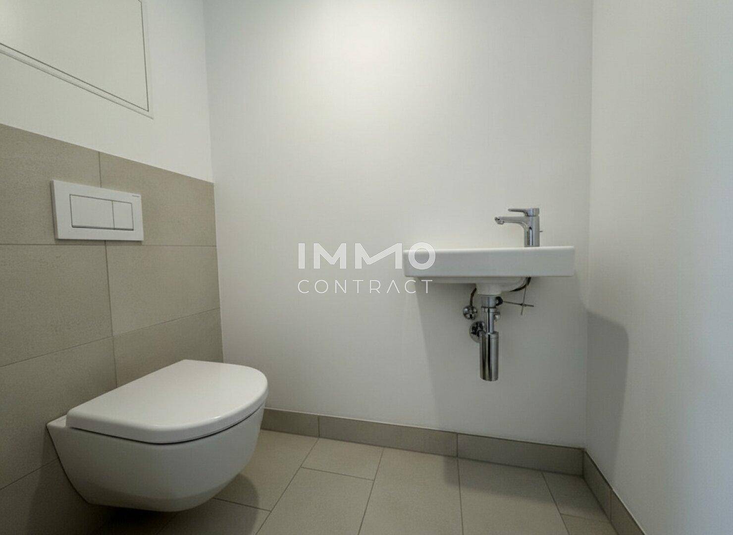 Modernes Gäste-WC mit Wand-WC und kleinem Waschbecken, hell gefliest.
