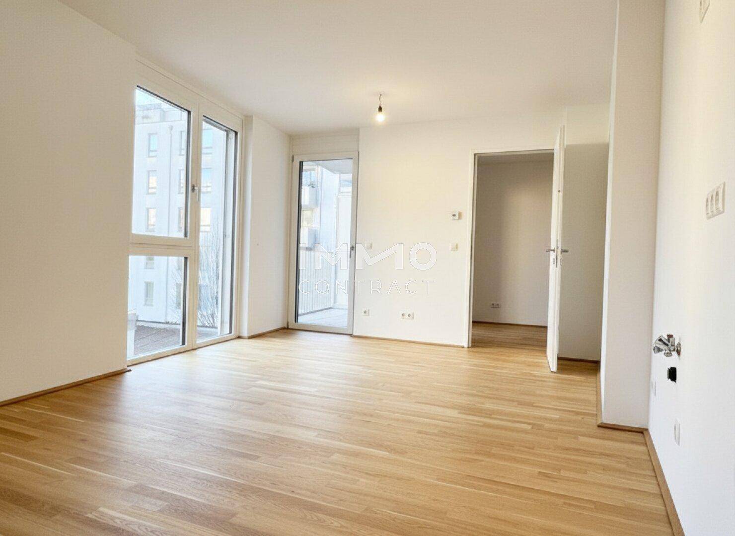 Lichtdurchfluteter Wohnbereich mit Holzboden und mehreren Zugängen zum Außenbereich.