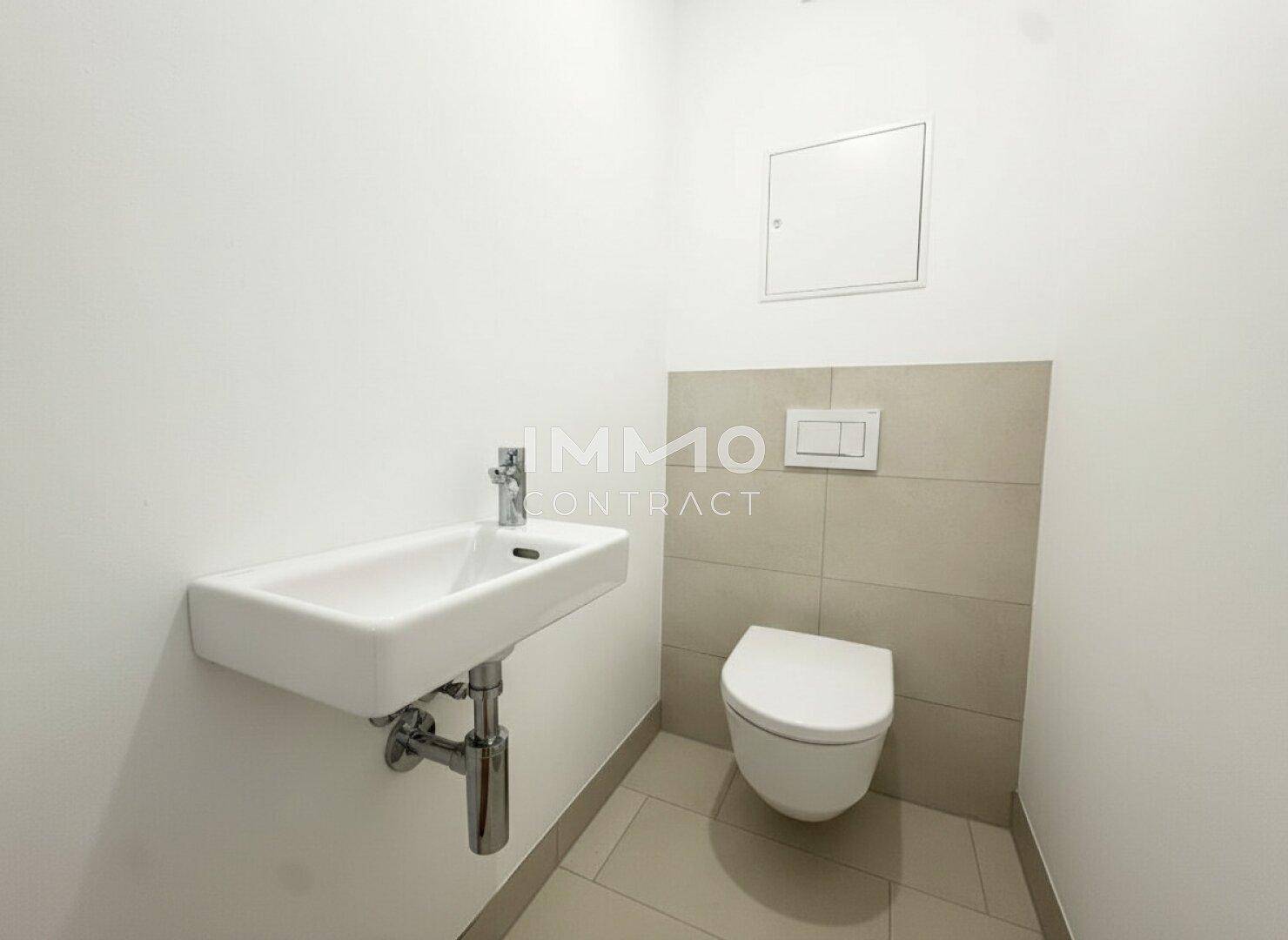 Kleines Gäste-WC mit wandhängender Toilette, Waschbecken und hellen Fliesen.