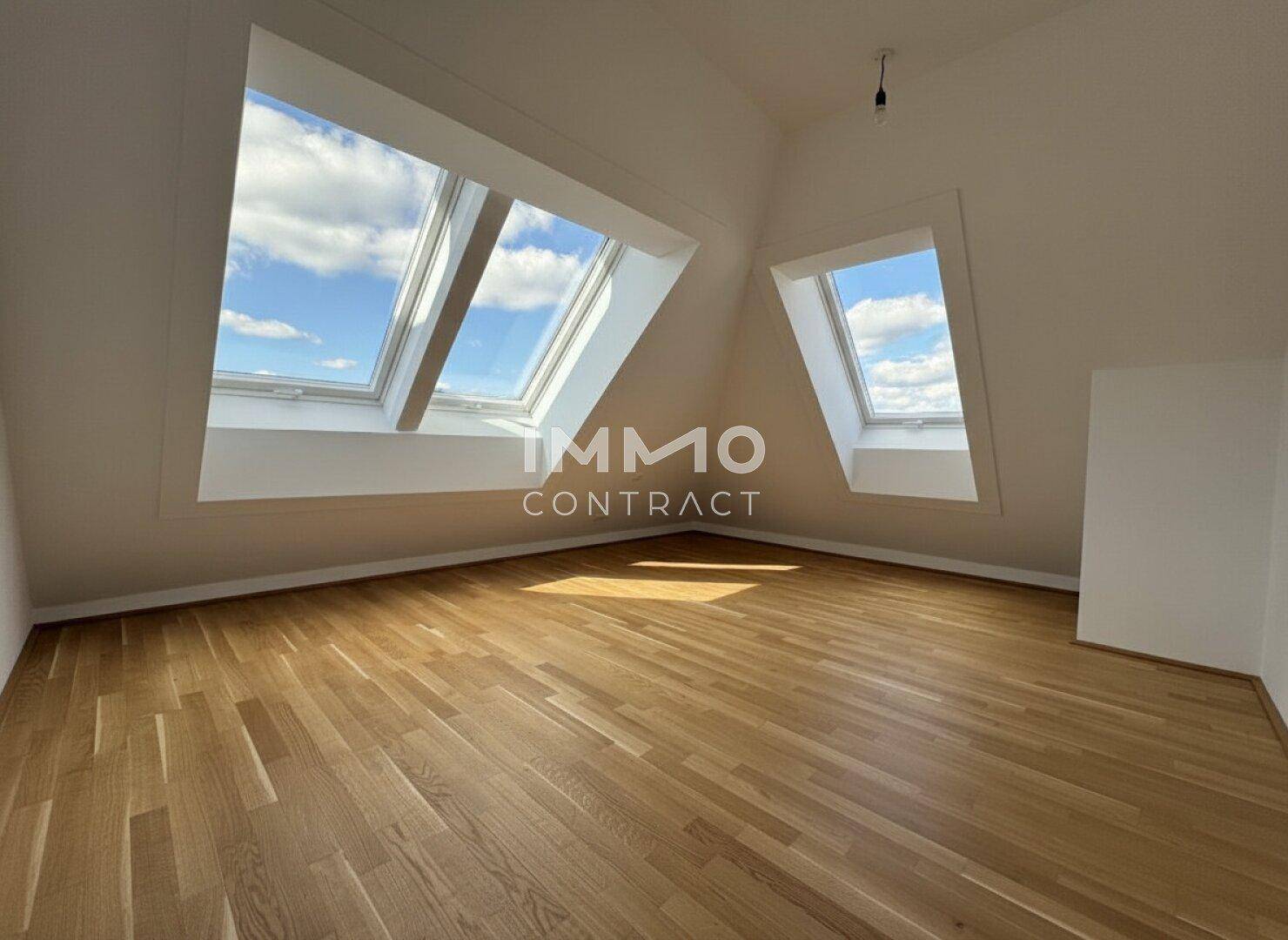 Helles Zimmer im Dachgeschoss mit Holzparkett und mehreren großen Dachfenstern für viel Licht.