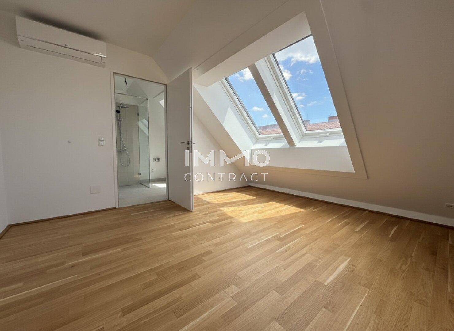 Schlafzimmer mit Parkettboden, Klimaanlage und direktem Zugang zu einem modernen Badezimmer.