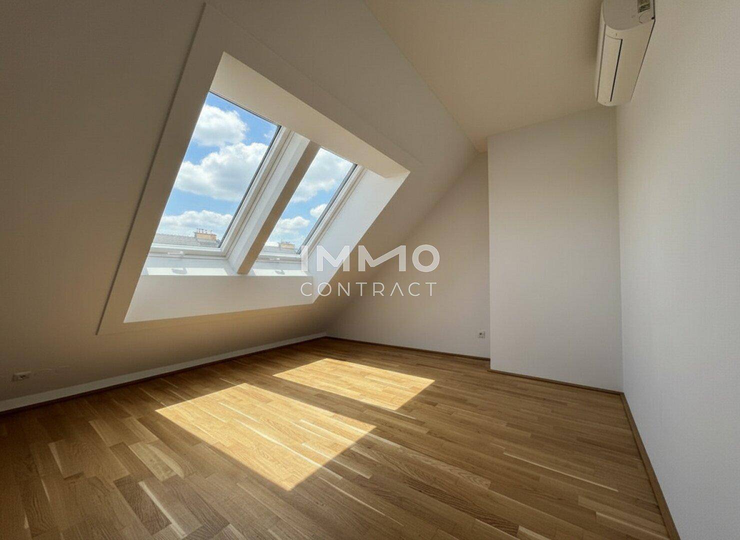 Helles Zimmer im Dachgeschoss mit Parkettboden, Klimaanlage und viel Tageslicht.