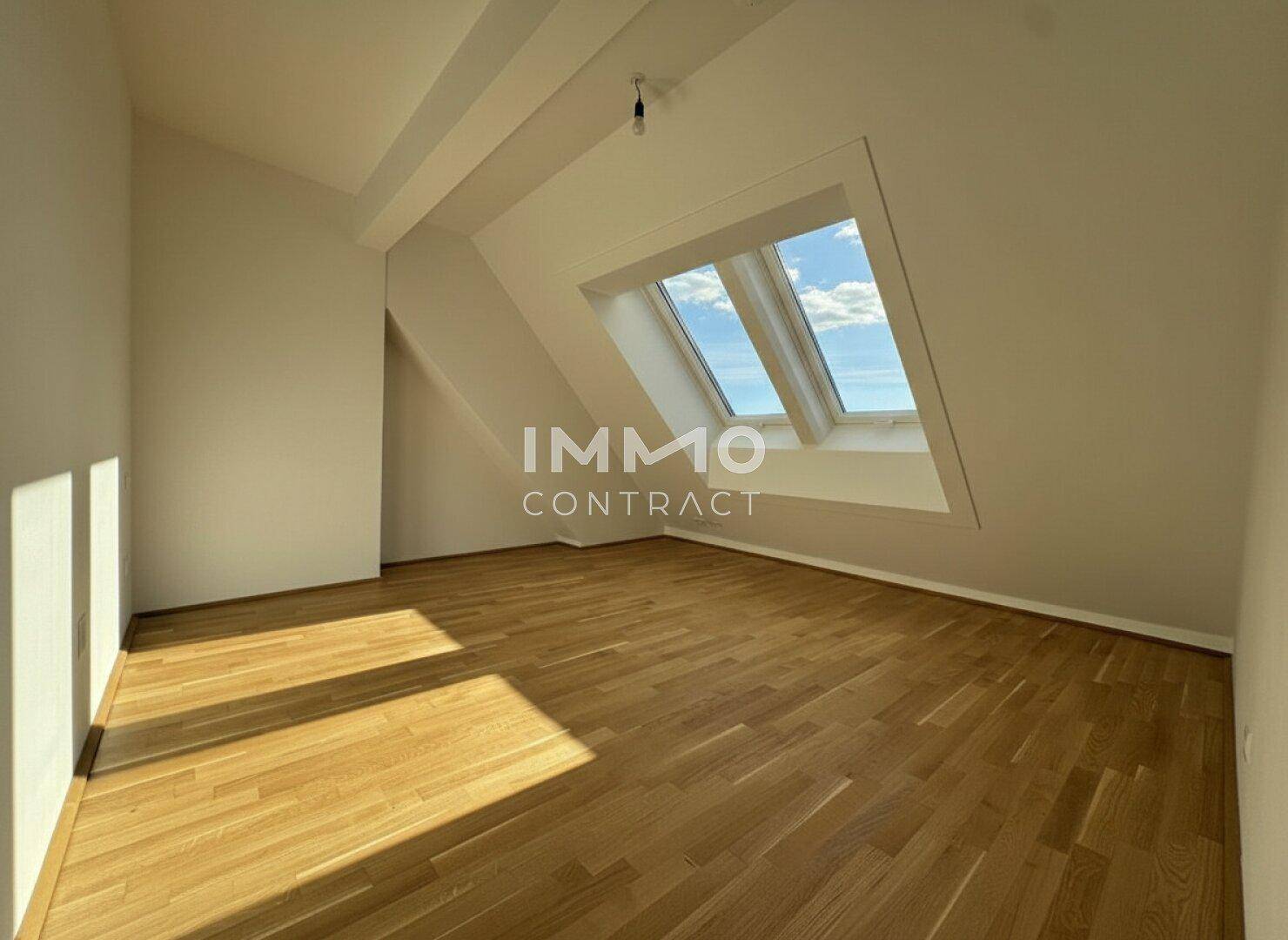 Geräumiges Zimmer im Dachgeschoss mit Parkettboden und schrägen Wänden, hell durch Dachfenster.