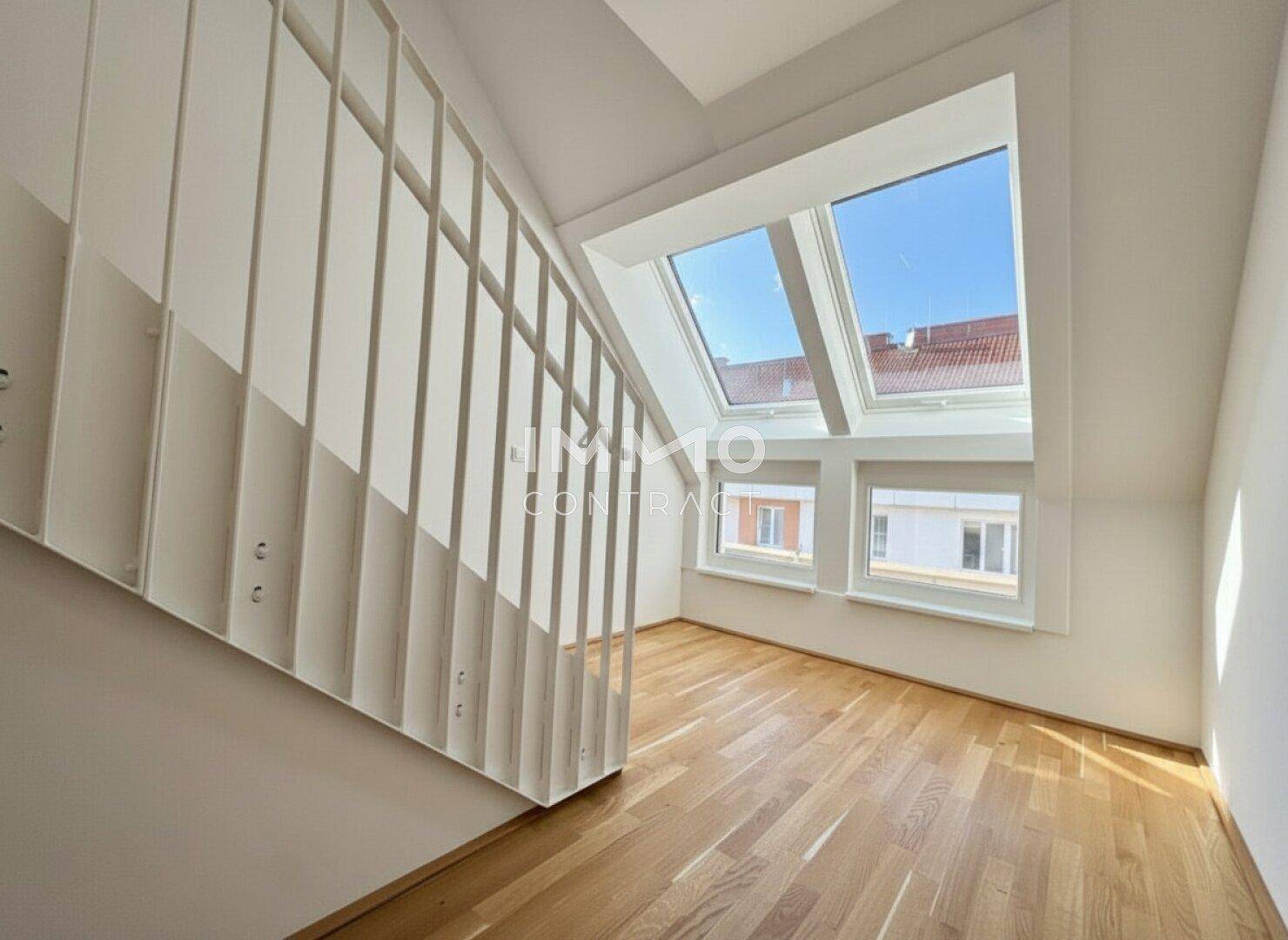 Heller Treppenbereich mit Holzparkett und mehreren Fenstern, darunter Dachfenster, für viel Licht.