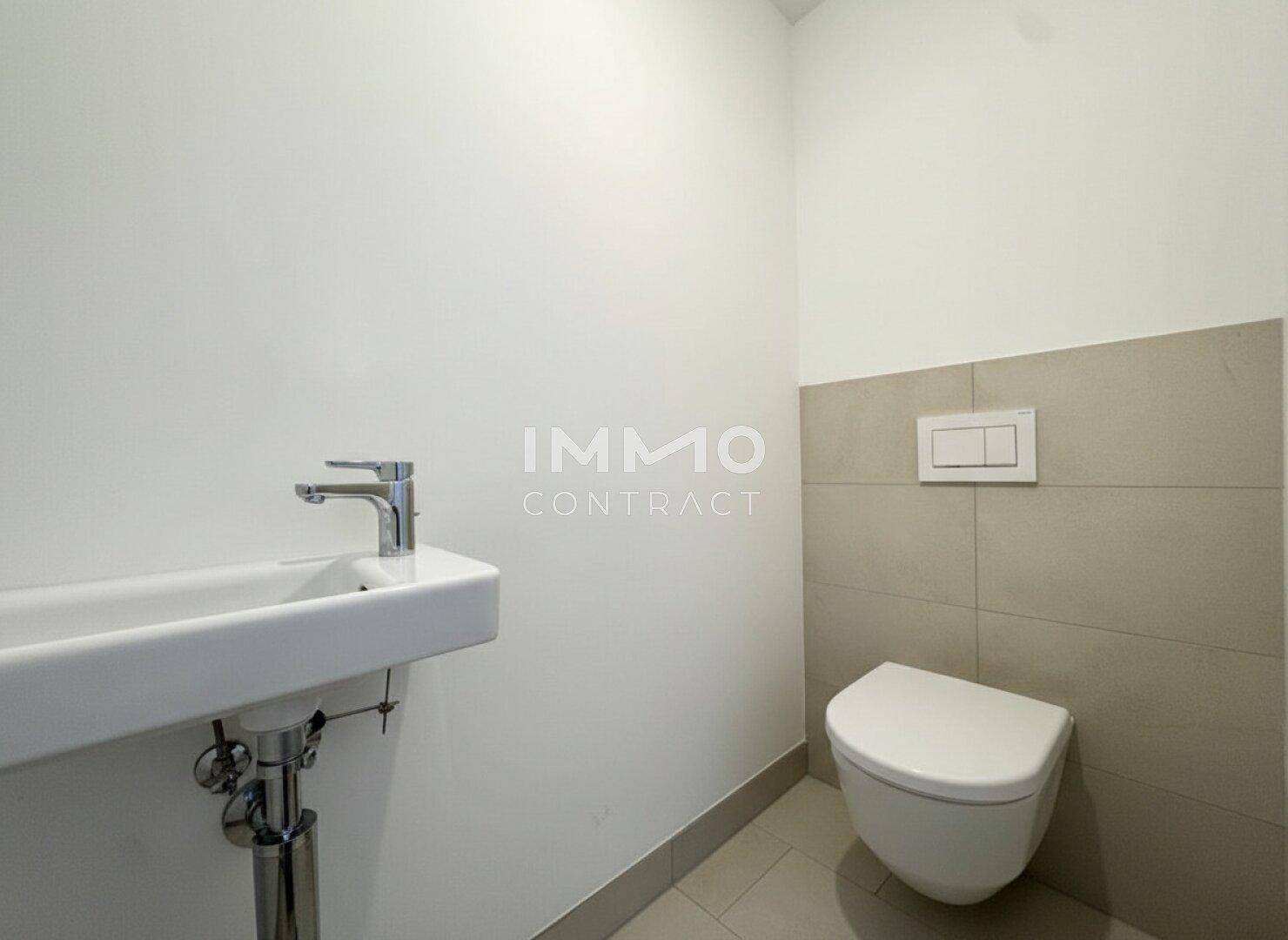 Gäste-WC mit wandhängender Toilette und kleinem Waschbecken, modern gefliest.