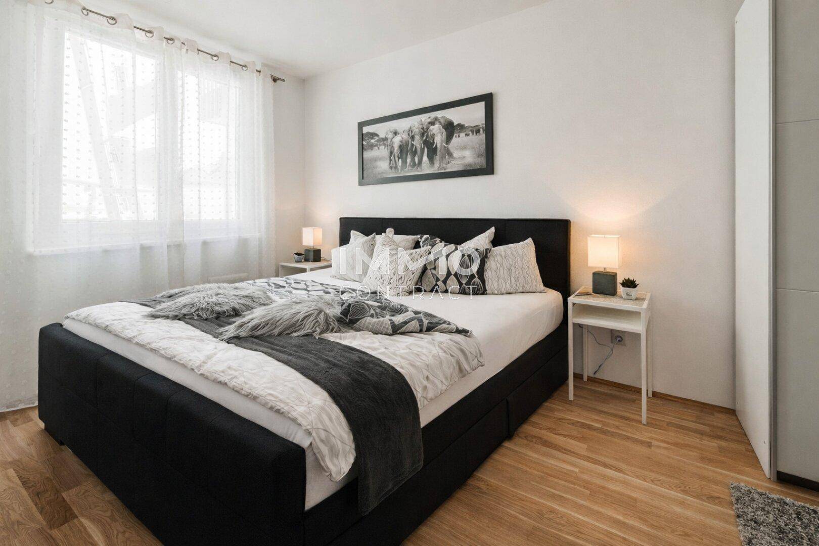 Gemütliches Schlafzimmer mit Doppelbett, Holzboden und großen Fenstern für viel Tageslicht.