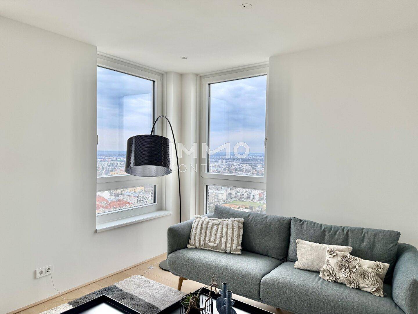 Gemütliche Ecke im Wohnzimmer mit Sofa und großen Eckfenstern, die einen Panoramablick bieten.