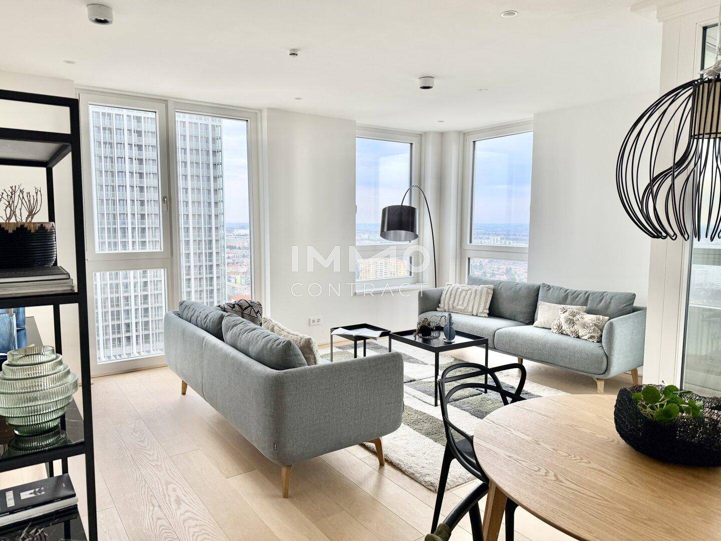 Geräumiges Wohnzimmer mit zwei bequemen Sofas, großen Fenstern und weitem Blick über die Stadt.