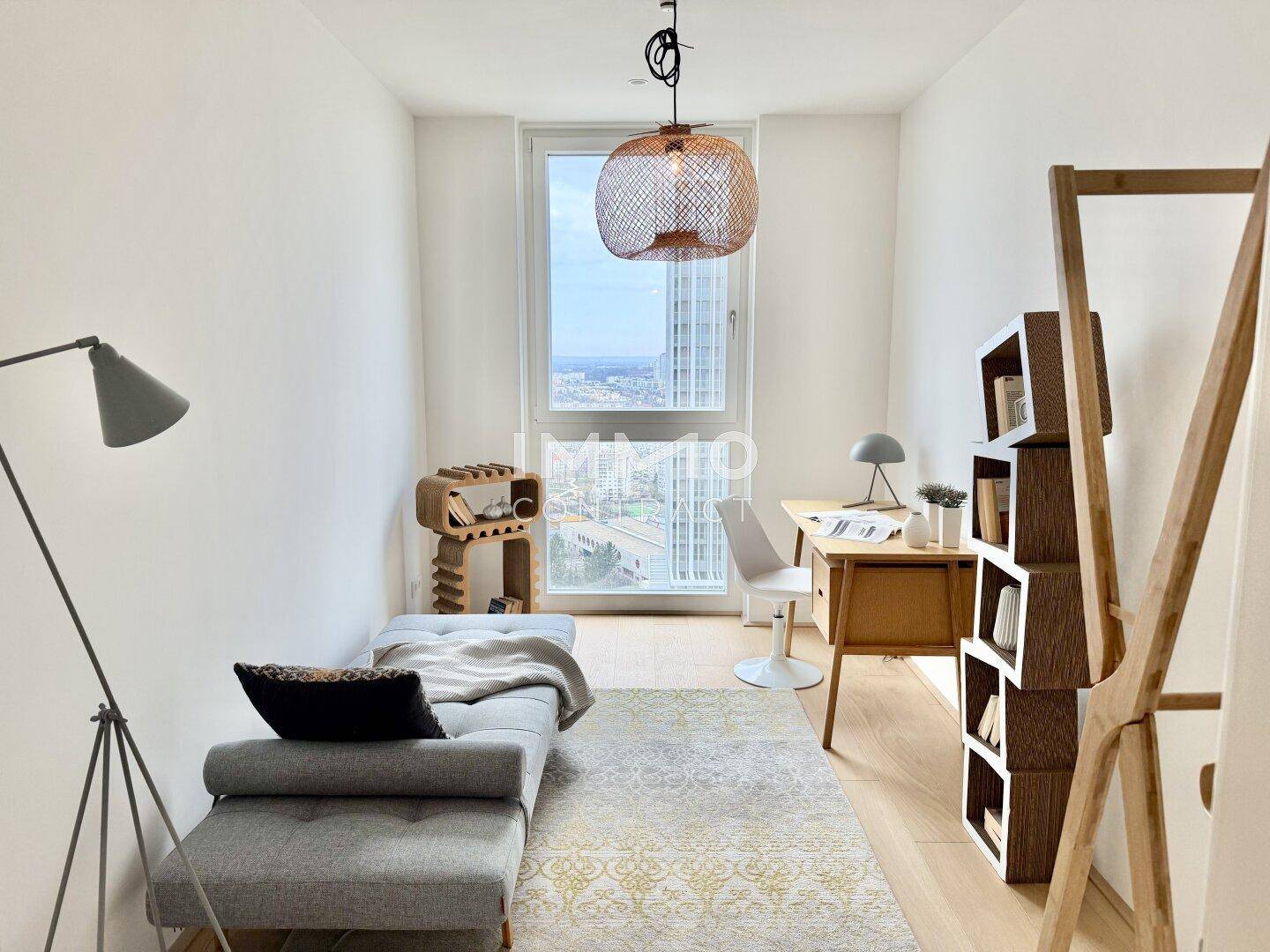 Helles Arbeitszimmer mit Schreibtisch, Tagesbett und großem Fenster mit Stadtblick.
