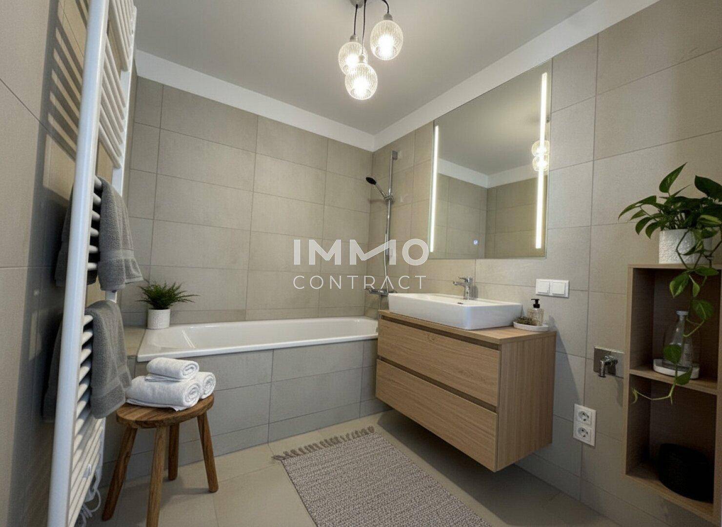 Modernes Badezimmer mit Badewanne, Waschtisch und beheiztem Handtuchhalter.