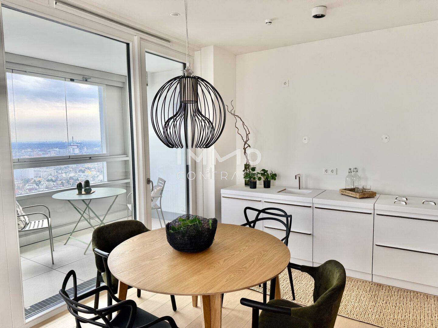 Moderner Essbereich mit Holztisch und integrierter Küchenzeile, mit weitem Blick über die Stadt.