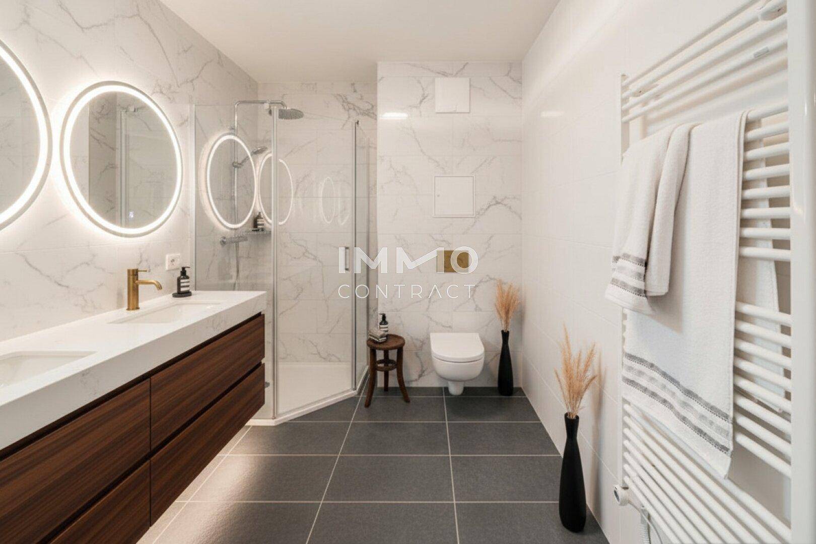 Modernes Badezimmer mit Doppelwaschbecken, begehbarer Dusche und beheiztem Handtuchhalter.