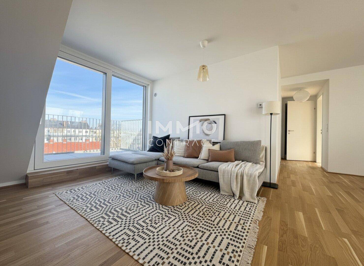 Modernes Wohnzimmer mit großem Sofa, Holzboden und Zugang zu einem Balkon oder einer Terrasse.