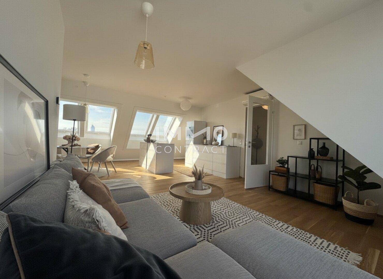 Heller Wohnbereich mit bequemer Couch, Holzboden und Blick auf die Stadt durch die Dachfenster.