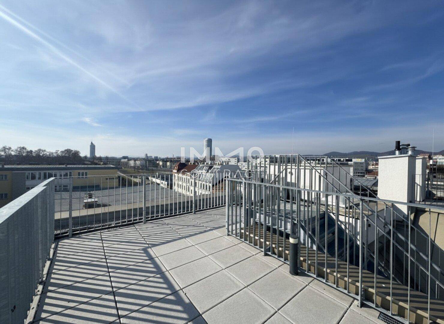 Weitläufige Dachterrasse mit Fliesenboden und Panoramablick über die städtische Umgebung.