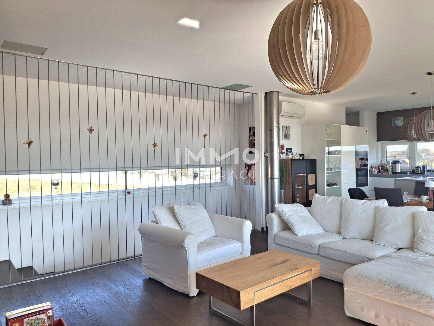 Gemütlicher Wohnbereich mit weißen Sofas, Holzboden und Blick in die offene Küche.