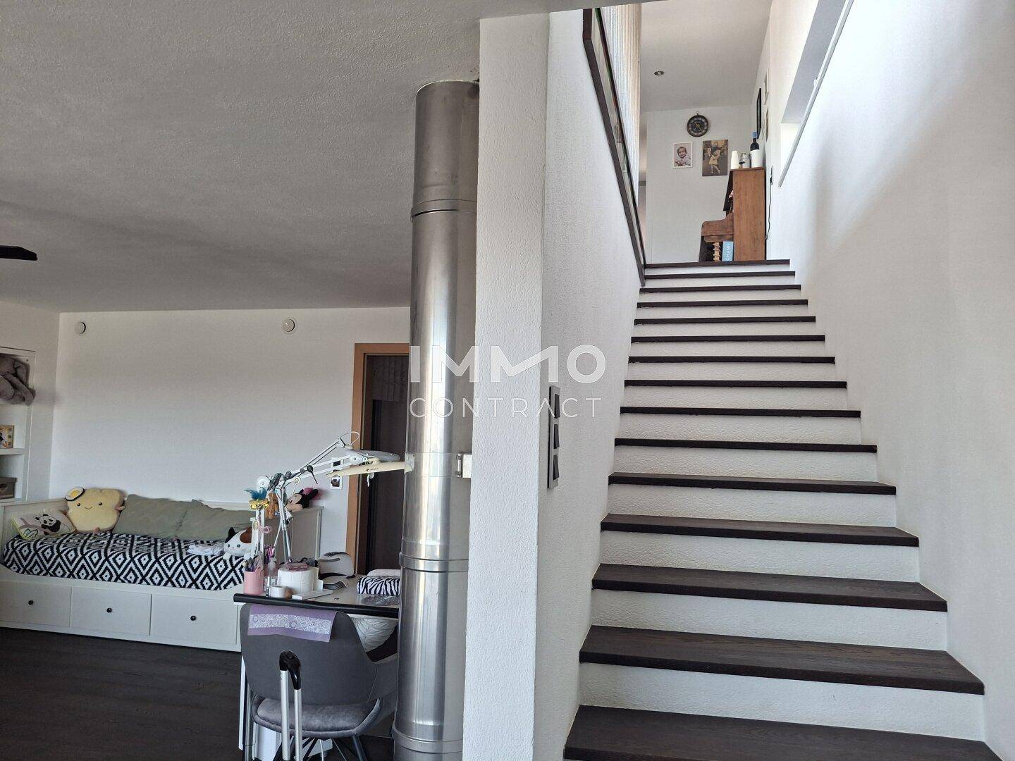Offener Wohnbereich mit Treppe und Blick auf einen weiteren Wohnbereich.