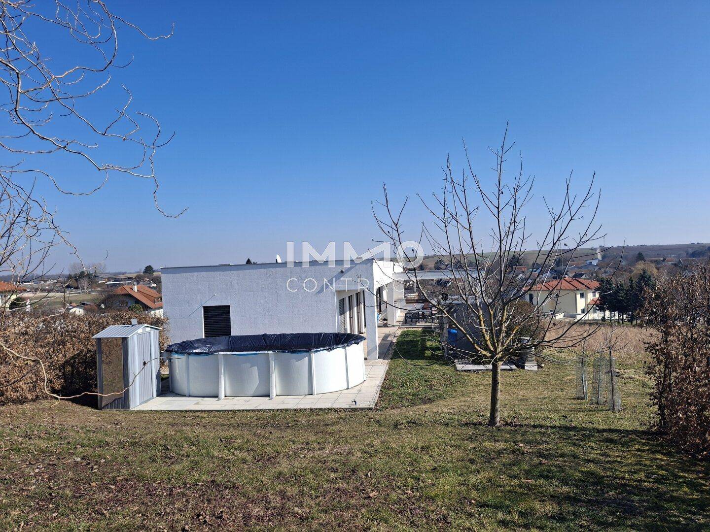 Modernes Haus vom Garten aus gesehen, mit oberirdischem Pool und viel Grün.