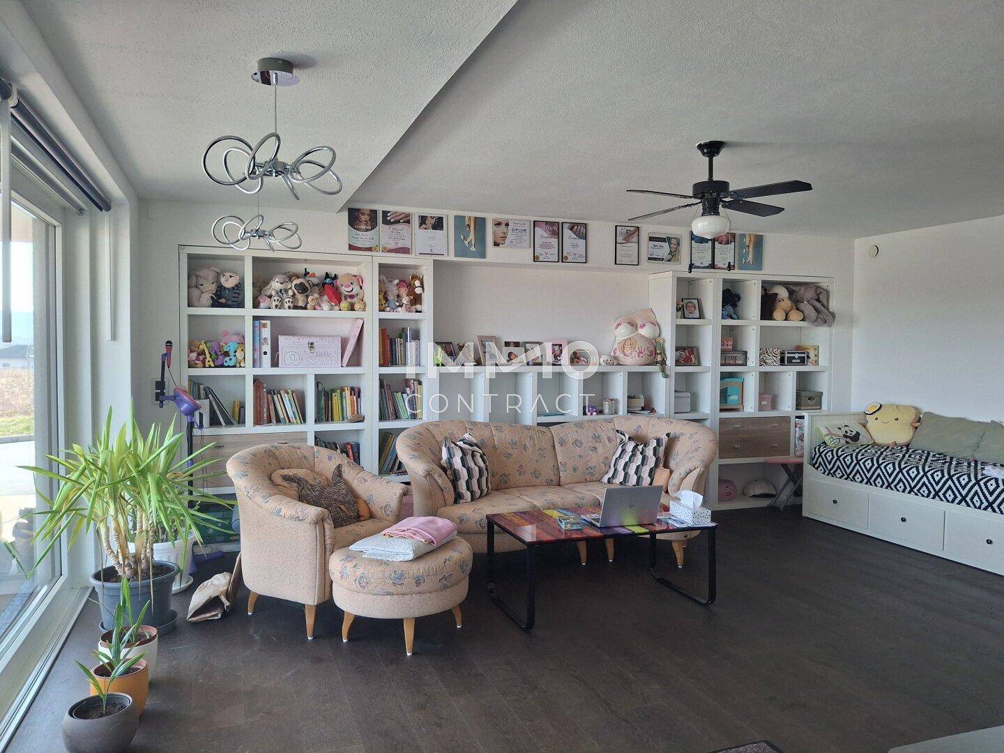 Geräumiges Wohnzimmer mit Einbauregalen, bequemen Sofas und Deckenventilator.