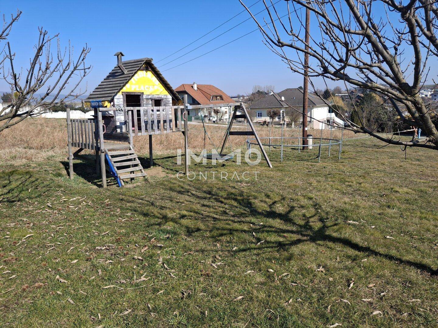 Spielplatz mit Schaukel und Rutsche im weitläufigen Gartenbereich.