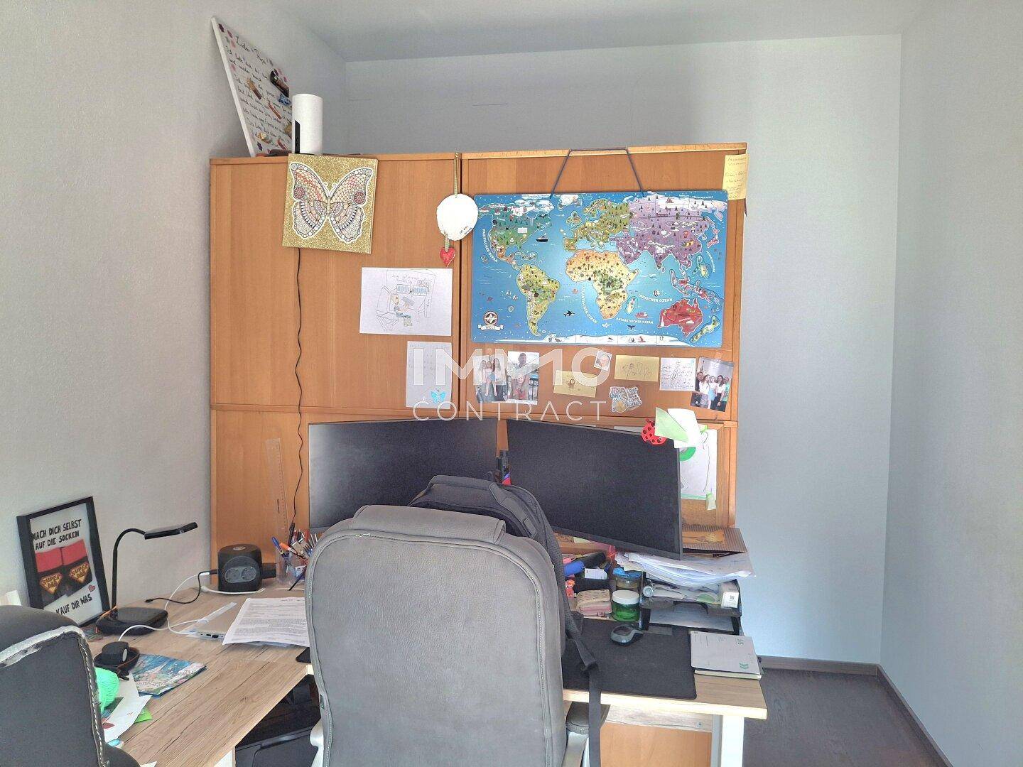 Funktionales Heimbüro mit großem Schreibtisch, zwei Monitoren und Holzschrank.